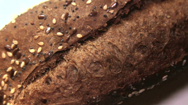 Crispy brown baguette with sesame seeds. Macro.