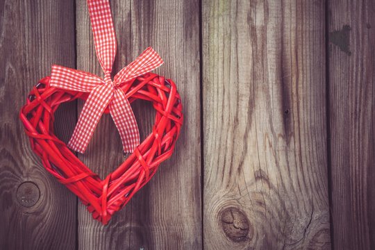 red heart with a ribbon on a wooden background