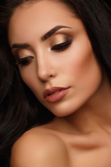 Obraz premium Portrait of a beautiful and attractive girl with thick wavy brunette hair and evening golden makeup
