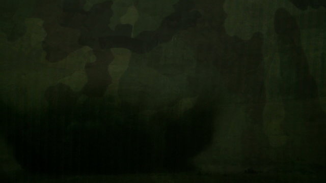 Slow motion explosion with camouflage pattern for a background.