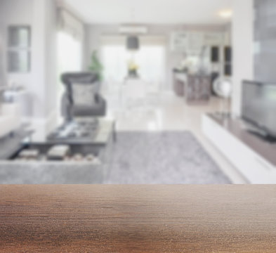 wooden table top with blur image of modern living room interior