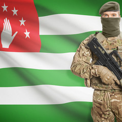 Fototapeta premium Soldier with machine gun and flag on background - Abkhazia