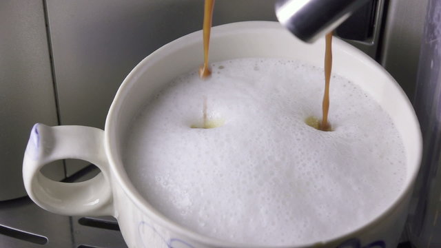 coffee is poured in a cup with the made foam milk, slow motion
