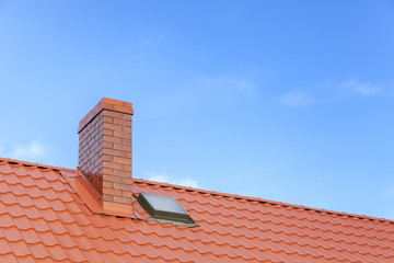 Roof with ceramic tile chimney against blue sky, space for text.