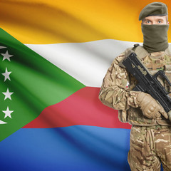 Fototapeta premium Soldier with machine gun and flag on background - Comoros