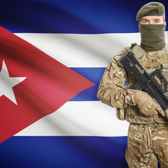 Fototapeta premium Soldier with machine gun and flag on background - Cuba