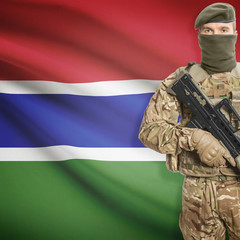 Fototapeta premium Soldier with machine gun and flag on background - Gambia