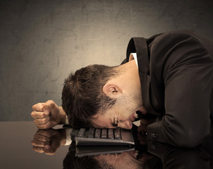 Obraz premium Frustrated businessman's head on keyboard