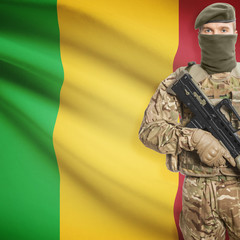 Fototapeta premium Soldier with machine gun and flag on background - Mali