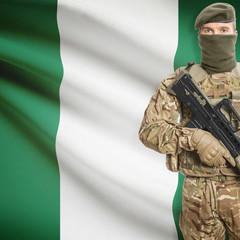 Fototapeta premium Soldier with machine gun and flag on background - Nigeria