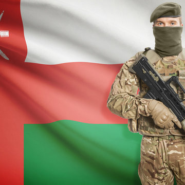 Soldier with machine gun and flag on background - Oman