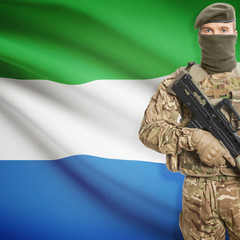 Fototapeta premium Soldier with machine gun and flag on background - Sierra Leone