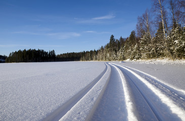 Snowmobile trail on a lake with a blue sky in background, picture from the North of Sweden.