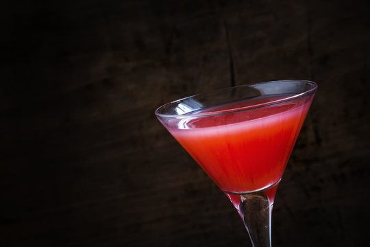 Red margarita cocktail in glass on old wooden background, dark t