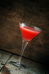 Red margarita cocktail in glass on old wooden background, dark t