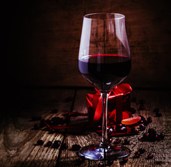 Red wine in a glass, a gift in the red packing on the old wooden