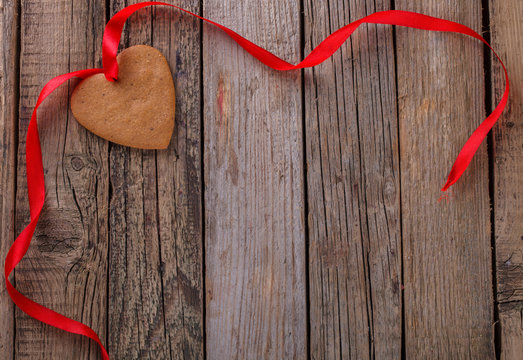 Valentine's day gingerbread heart with red ribbon on wooden background.Vintage style.Copy space.
