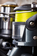 closeup fishing reel on wooden board background