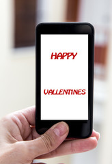 Hands holding mobile phone with sign valentines day