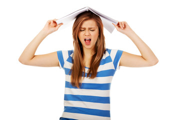 Screaming teenage woman with notebook on head