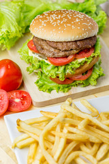 Delicious hamburger and french fries on wooden table