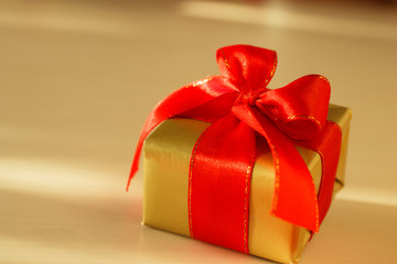 Small golden box with gift tied red bow