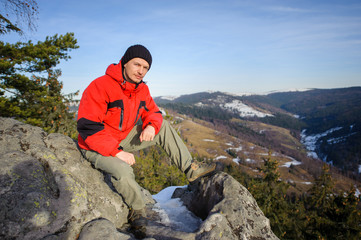 Fototapeta premium Young tourist sitting on top of the mountain and looking towards