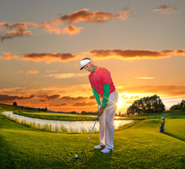 Man playing golf against colorful sunset