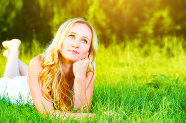 Naklejka na ściany i meble beautiful happy dreamy woman in summer on nature lying on grass