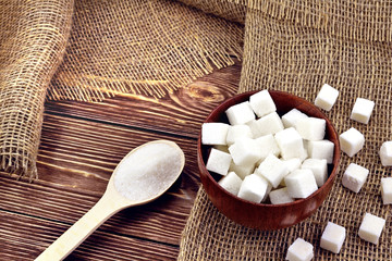 Photo of a wooden spoon and a sugar bowl with sugar on the table