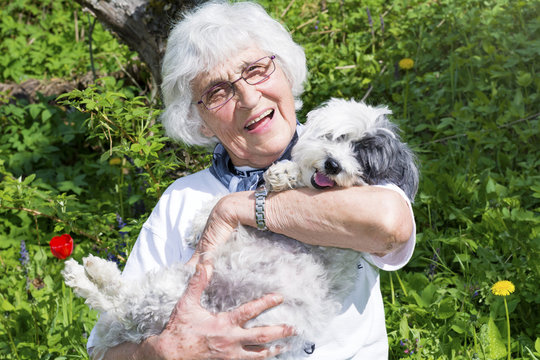 beautiful Senior smiling woman hugging her small white poodle dog in the mountain
