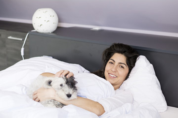 young woman sleeping with her small  dog in a human  bed. 