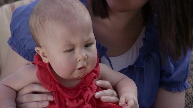 Up close slow motion of woman bouncing baby girl on her knee.