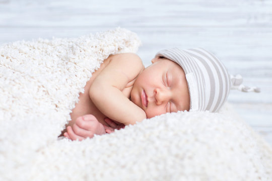 adorable newborn boy sleeps on the white blanket with background in the hat