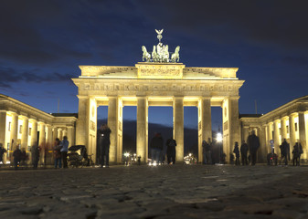 Obraz premium The floodlit Brandenburg Gate in Berlin with a few fleeting shadows of anonymous Berliner's - Symbol of Germany.