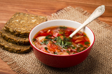 Borsht - traditional russian and ukranian beetroot soup in red bowl on wooden background.