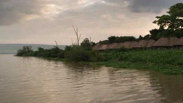Row of grass-roofed dwellings along lake