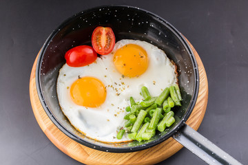 Fried egg on a pan served with tomato and asparagus