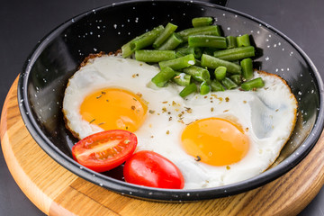 Fried egg on a pan served with tomato and asparagus