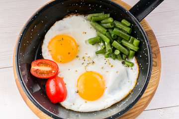 Fried egg on a pan served with tomato and asparagus