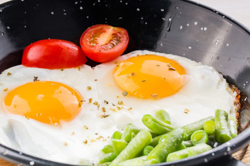 Fried egg on a pan served with tomato and asparagus