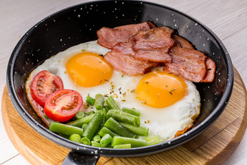 Fried egg on a pan served with tomato and asparagus