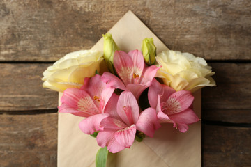 White eustoma and pink alstroemeria in envelope on wooden background