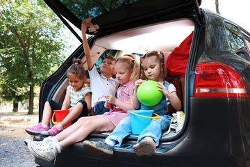 Fototapeta na wymiar Three beautiful girls and boy sit on a car trunk and laughing
