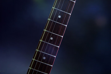 Part of electric guitar, on dark lighted background