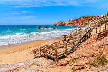 Wooden steps to Praia do Amado beach with ocean waves hitting shore, Algarve region, Portugal