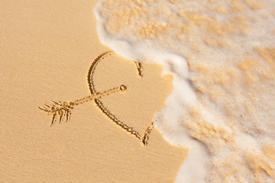 Wave washes over heart in the sand. Love  & heart break concept.
