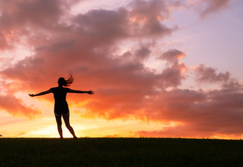 Happy woman jumping against sunset. Freedom concept. Enjoyment.
