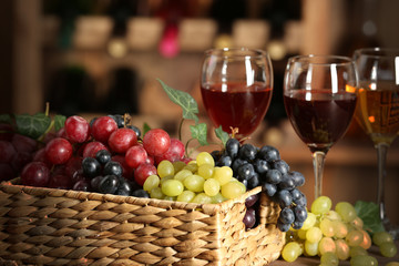 Grape in wicker box on a table on wine bottles background