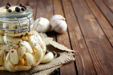 Canned garlic with spices on wooden background